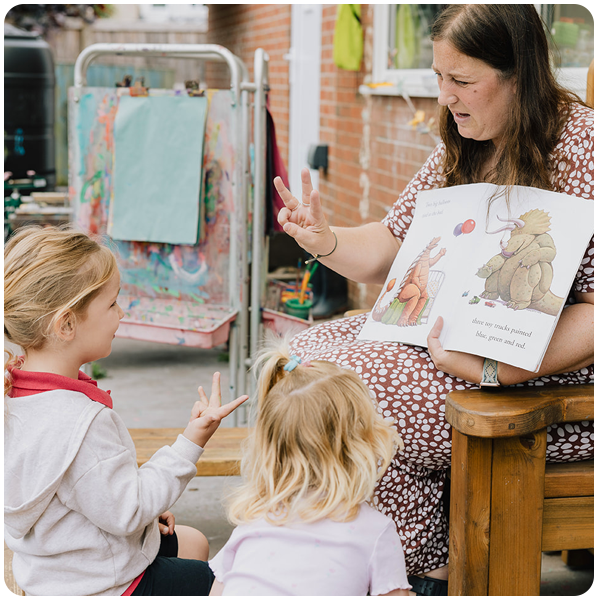 Practitioner reading with two girls outside